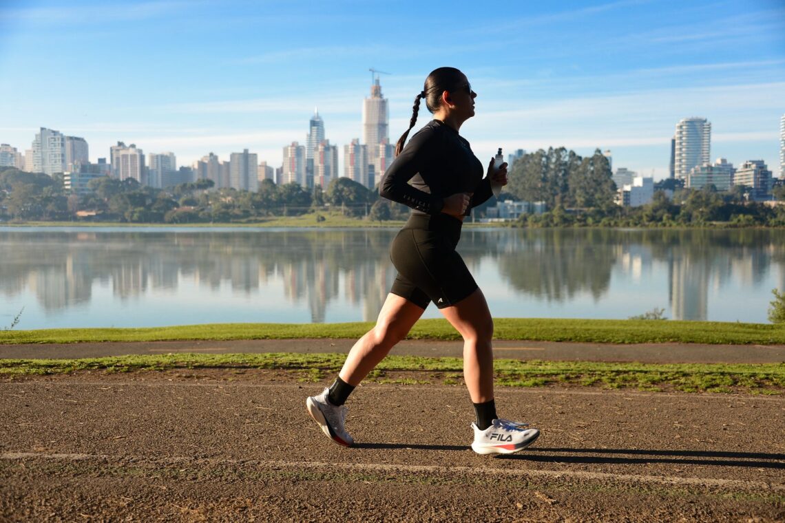 woman jogging by lake with cityscape background