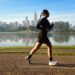 woman jogging by lake with cityscape background
